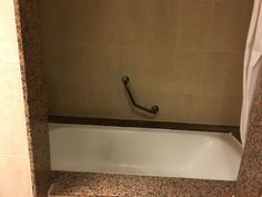 an empty bathtub in a bathroom with marble walls and flooring on the sides