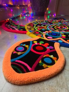 three brightly colored rugs on the floor in front of a doorway with colorful lights