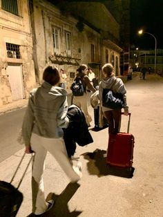 some people are walking down the street with their suitcases and one person is pulling luggage