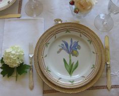 a table set with plates, silverware and flowers