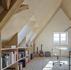 a room with bookshelves, desk and guitar in it's center area