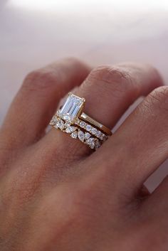 a woman's hand with two rings on it and an engagement ring in the middle