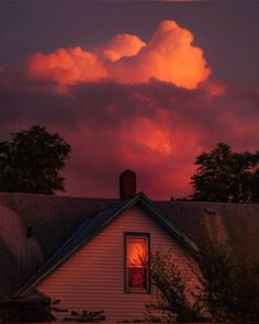 the sun is setting over a house with clouds in the sky and trees around it