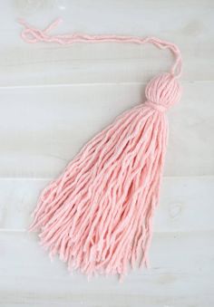 a pink tasselle on a white wooden surface