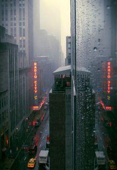 a city street filled with lots of traffic next to tall buildings in the foggy day