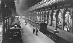 an old black and white photo of people at a train station