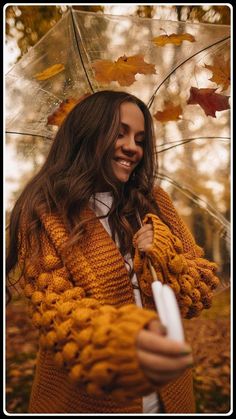 a woman is holding an umbrella in the fall leaves while she smiles for the camera