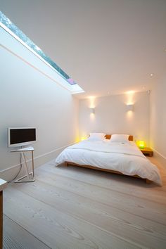 a bed sitting under a skylight in a bedroom next to a desk and chair