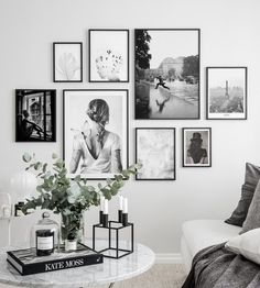 black and white photographs hang on the wall above a table with candles, vases and flowers