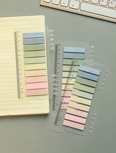 two pieces of colored paper sitting next to a keyboard