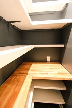 an empty room with some shelves in the corner and wood flooring on the other side