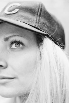 a black and white photo of a woman with blonde hair wearing a baseball cap on her head