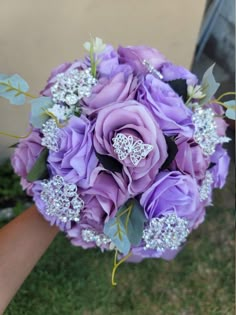 a bridal bouquet with purple roses and diaper brooches