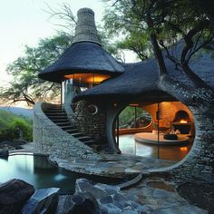 a house made out of rocks with a spiral staircase leading up to the top floor