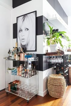 a bar cart in the corner of a room with pictures on the wall behind it