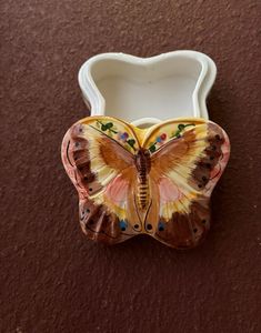 a butterfly shaped container sitting on top of a brown table next to a red wall