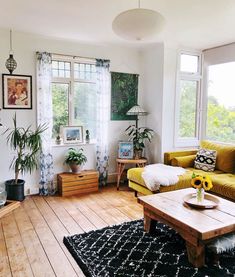 a living room filled with furniture and lots of windows next to a wooden floor covered in plants