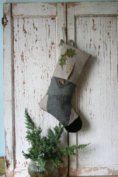 a christmas stocking hanging on the side of an old door with a potted plant