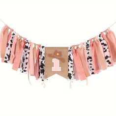 a pink and black cow print banner hanging from a clothes line with the number one on it