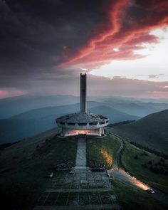 a building on top of a hill under a cloudy sky