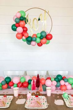 a table topped with plates and cups filled with desserts next to a balloon arch