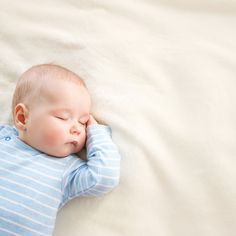 a baby sleeping on top of a white blanket