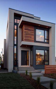 a modern house with wood and glass on the front door, stairs leading up to it