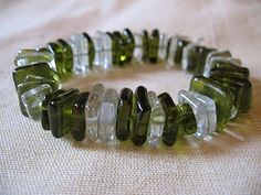 a bracelet made out of green and white glass beads on top of a cloth covered table