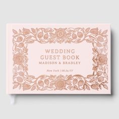 the wedding guest book is shown in pink with gold foil flowers and leaves on it