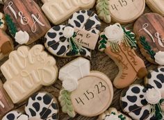 decorated cookies with names and date displayed on wooden table top, including cow print design