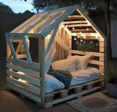 a bed made out of pallets with lights in the roof and pillows on top