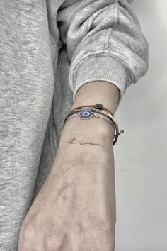 a woman's wrist with a small tattoo on the left side of her arm