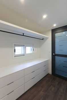 an empty room with white cabinets and drawers