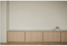 an empty room with some books on top of the cabinets and a wooden object in front of it