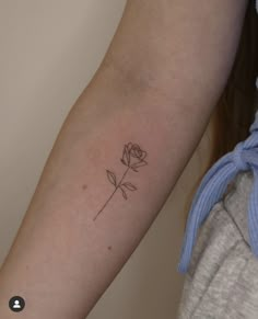 a woman's arm with a single rose tattoo on the left side of her arm