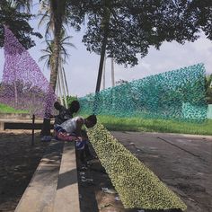 two people are sitting on a bench near some trees