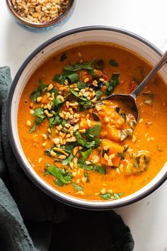 a white bowl filled with soup next to a spoon