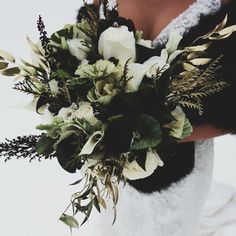 a bride holding a bouquet of flowers and greenery