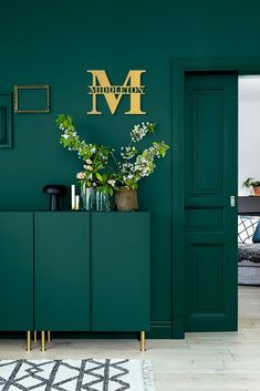 a living room with dark green walls and white rugs on the floor next to a cabinet