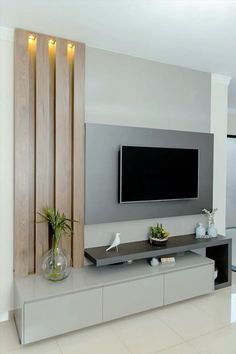 a flat screen tv mounted to the side of a wall next to a vase with plants