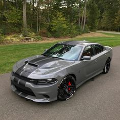 a gray car parked on the side of a road next to some grass and trees