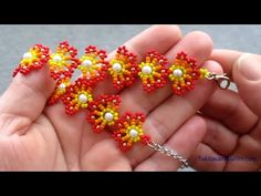 a hand holding a small beaded necklace in red, yellow and white