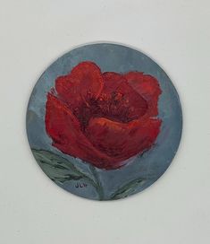 a painting of a red flower on a blue plate