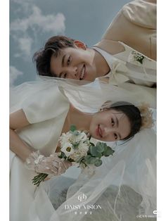 two women in white dresses and bouquets posing for a photo with the sky behind them