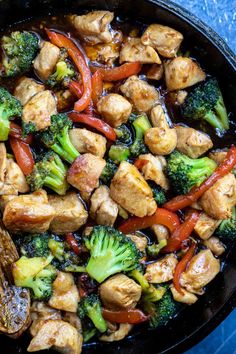 chicken and broccoli stir fry in a skillet on a blue counter top