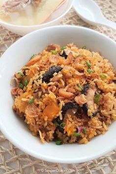 a white bowl filled with rice and meat on top of a table next to another bowl