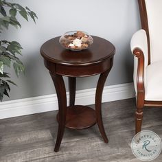 a wooden table with a bowl of food on it next to a chair and potted plant