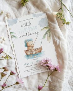 a little fisherman is on the way baby shower book next to some wildflowers