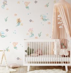 a baby's room with mermaid wall decals and a crib in the foreground