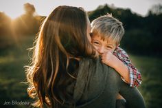 a woman holding a boy in her arms while the sun shines down on them